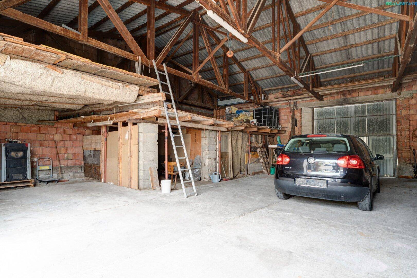 Große Scheune oder Garage mit Auto, hoher Holzkonstruktion und Ziegelwänden.
