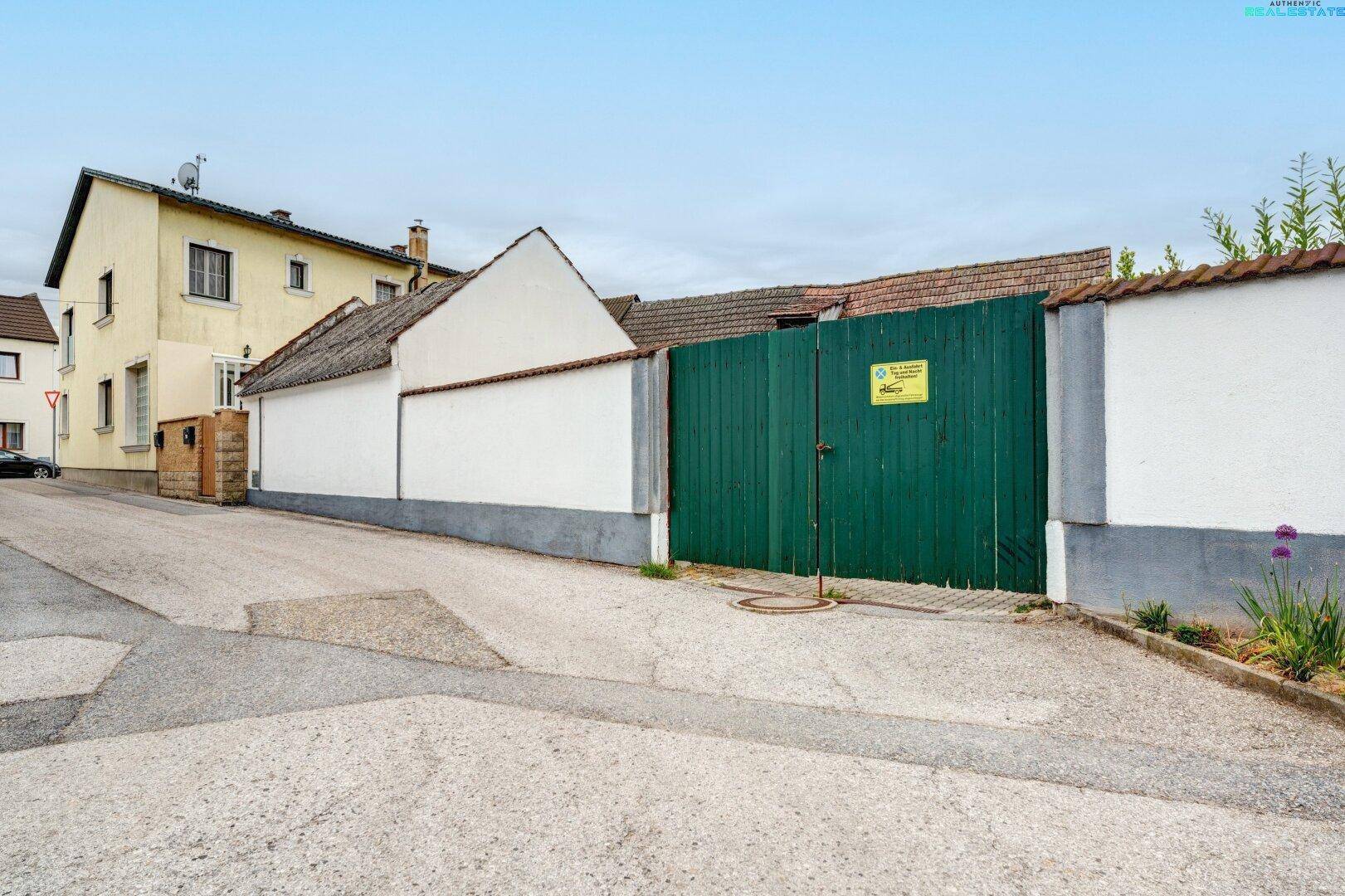 Ansicht des Hauses von der Straße mit einer großen grünen Holztür und einer weißen Mauer.