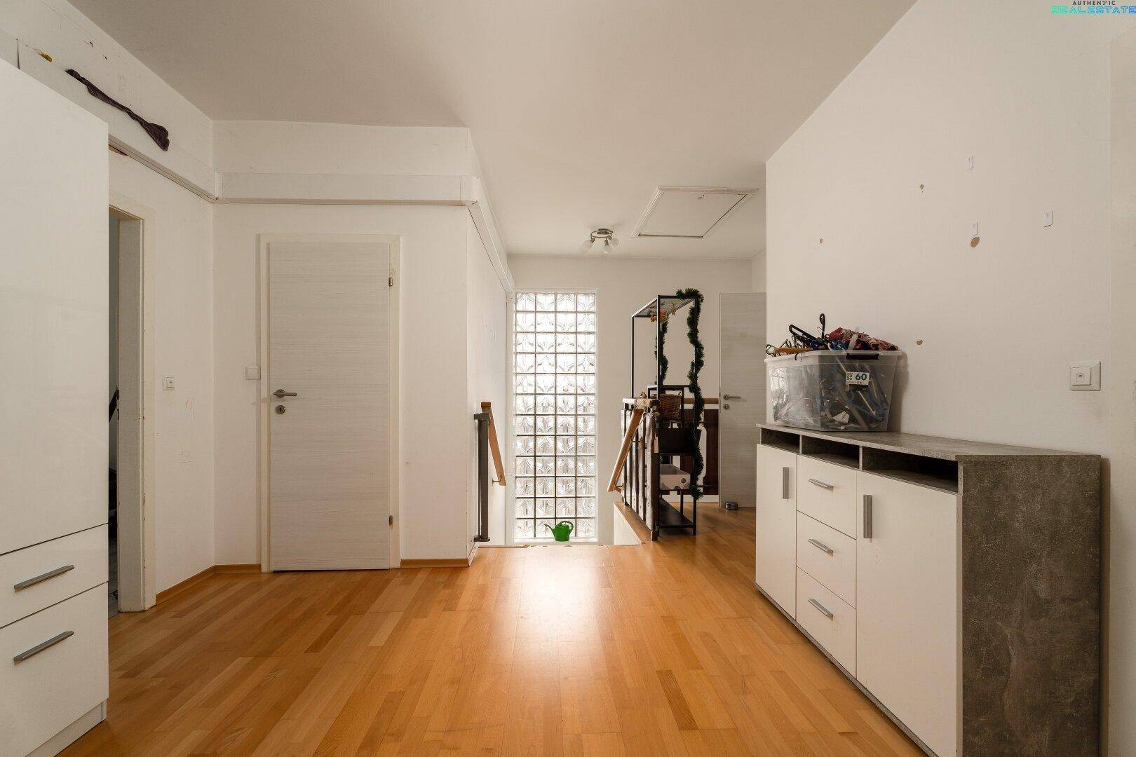 Heller Flur mit Holzfußboden, weiß gestrichenen Wänden und einer dekorativen Glasbausteinwand.