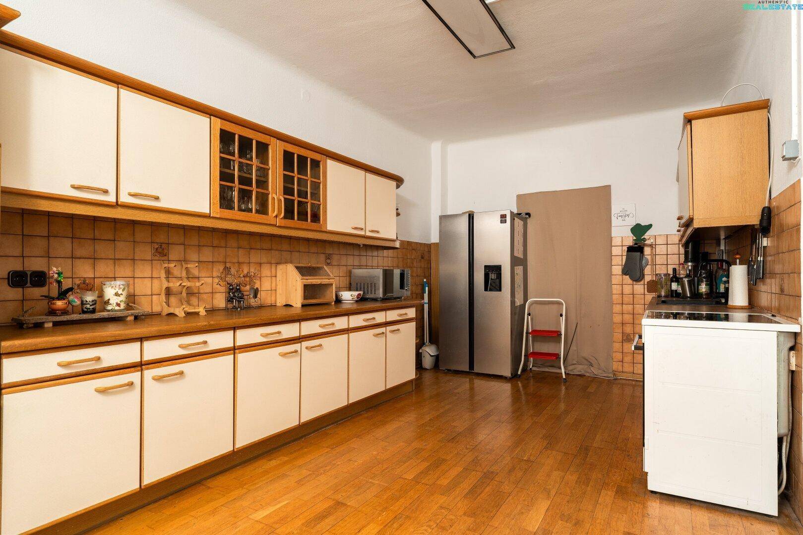 Geräumige Küche mit hellen Holzschränken, gefliestem Spritzschutz und großem Kühlschrank.