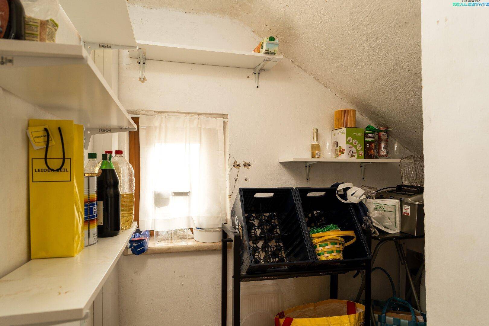 Kleiner Abstellraum mit Regalen, Fenster und schräger Decke, ideal zur Aufbewahrung.