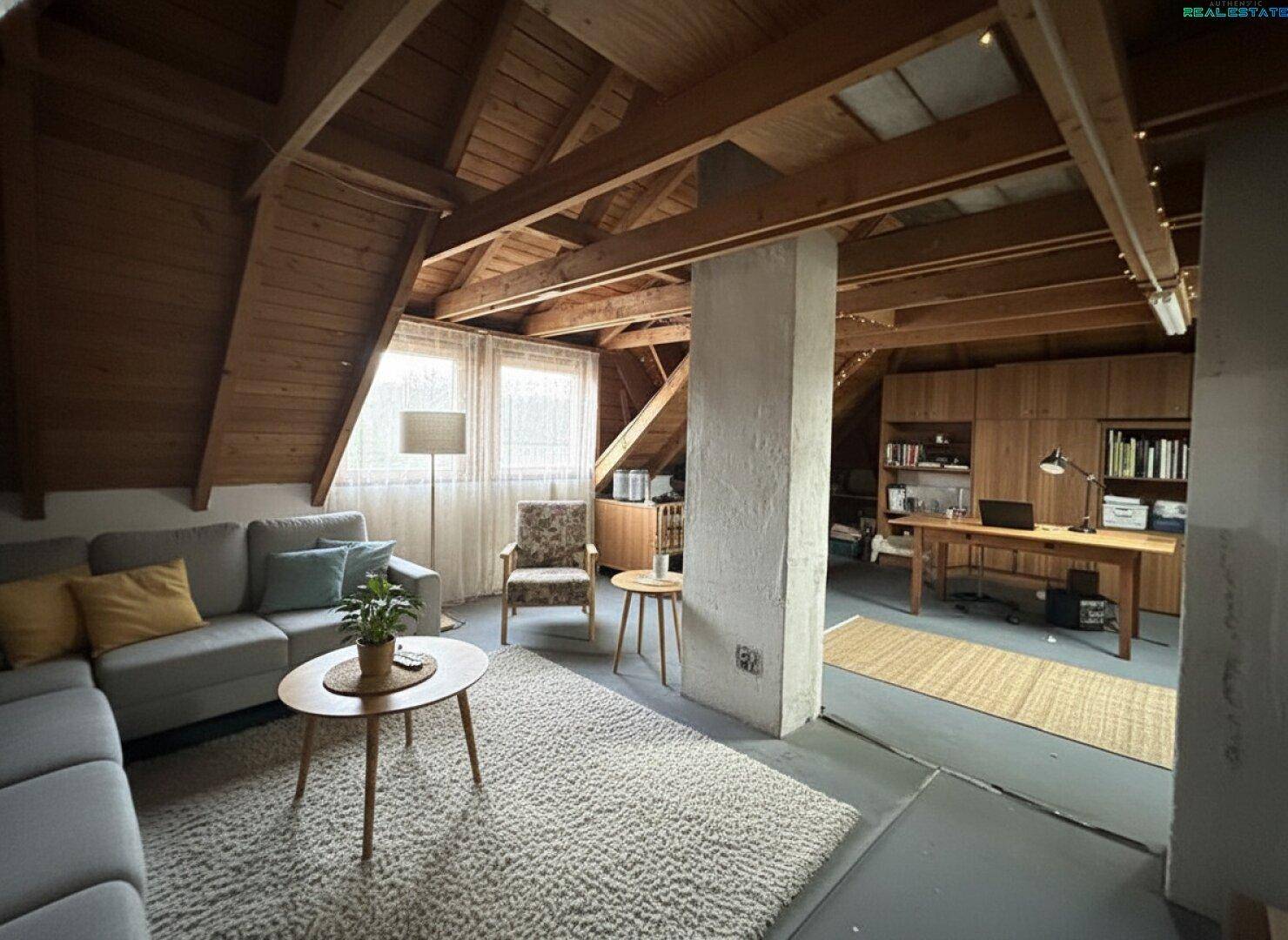 Ausgebauter Dachboden mit Wohnbereich, Holzbalken und Arbeitsplatz, modern eingerichtet.