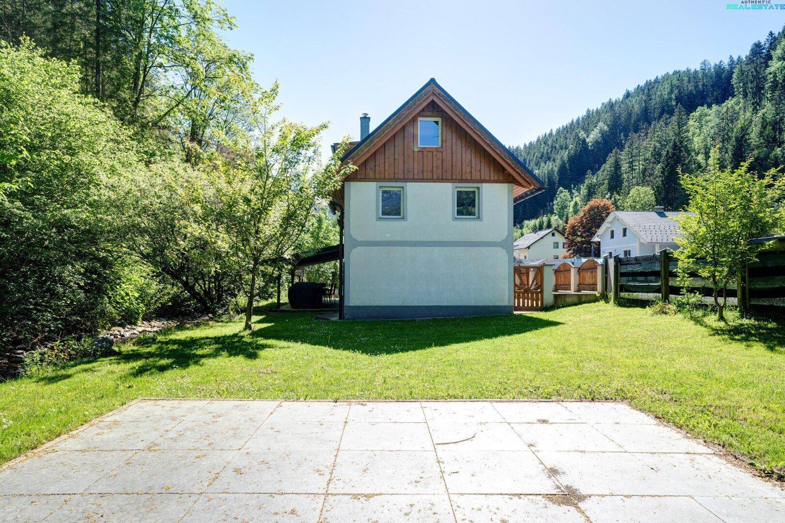 Rückseite des Hauses mit großer Rasenfläche und Bergblick.