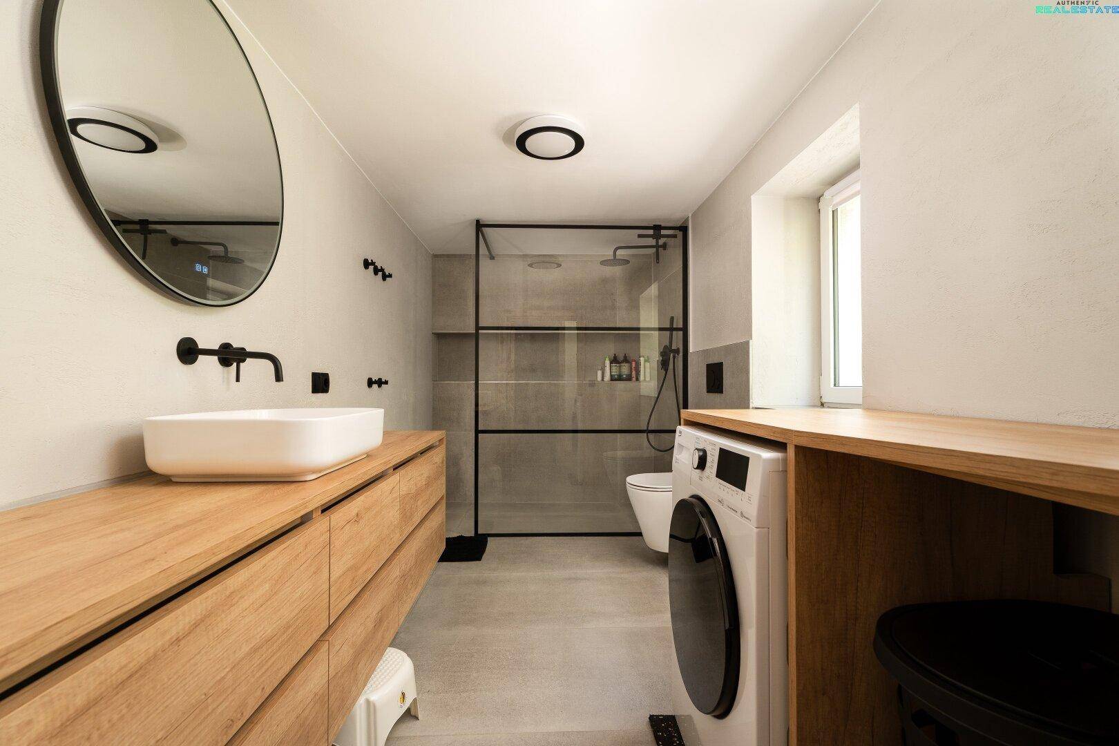 Modernes Badezimmer mit begehbarer Dusche, Holzwaschtisch und Waschmaschine.