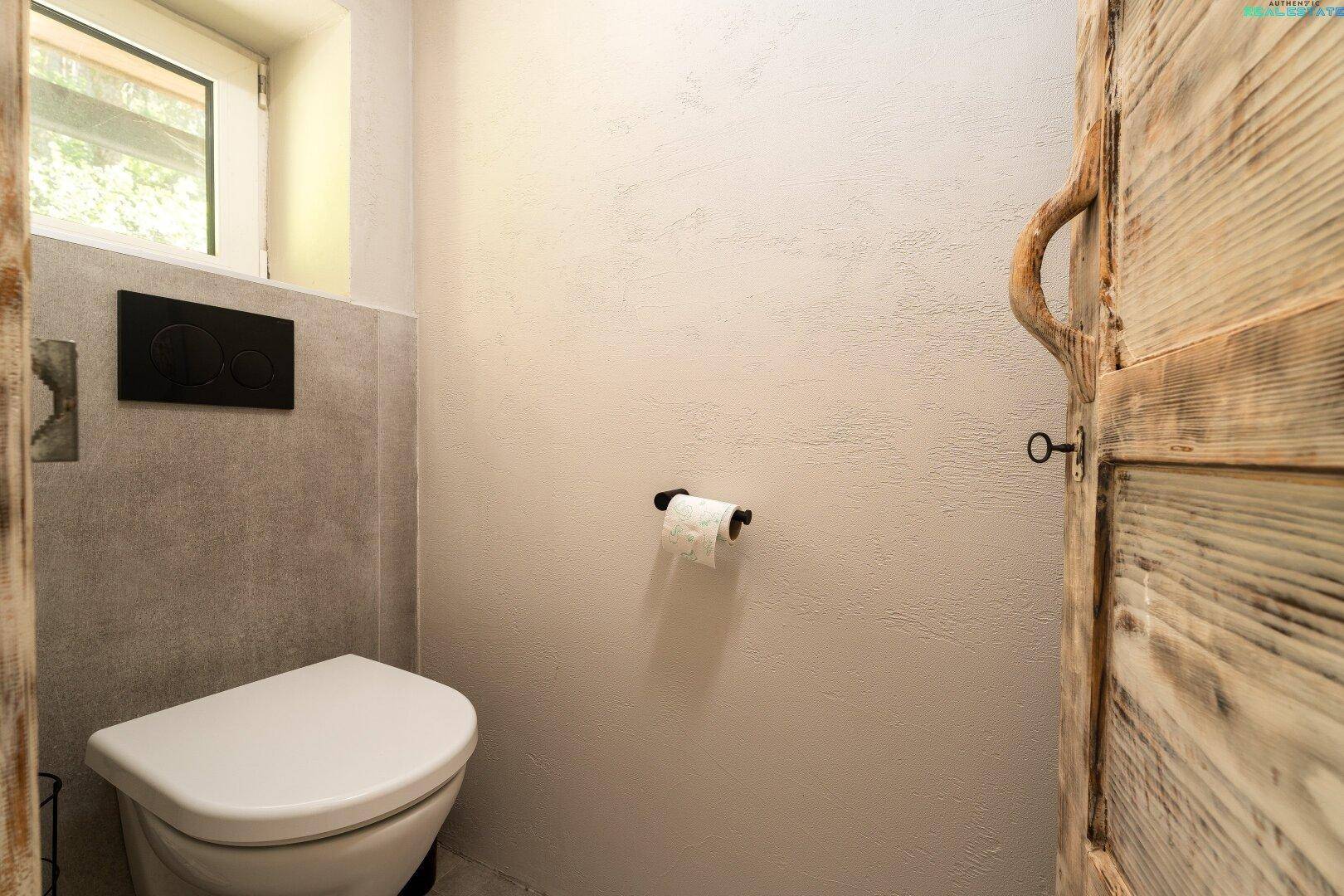 Separate Toilette mit Wand-WC und Fenster.