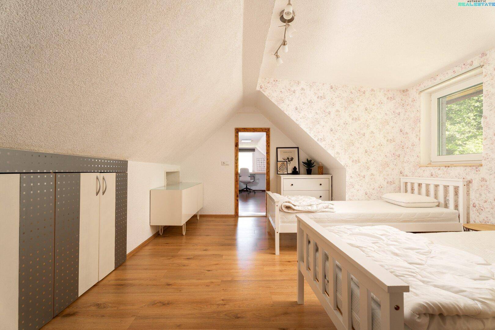 Helles Kinderzimmer im Dachgeschoss mit Holzboden und Stauraum.