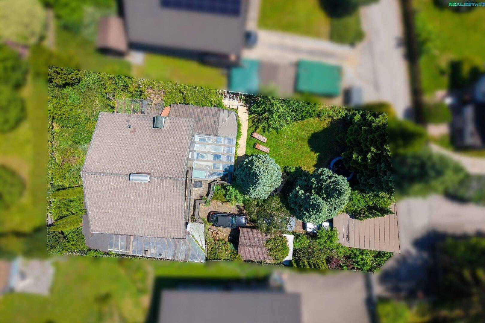 Vogelperspektive des Anwesens mit Haus, Garten, Parkplatz und angrenzenden Grundstücken.