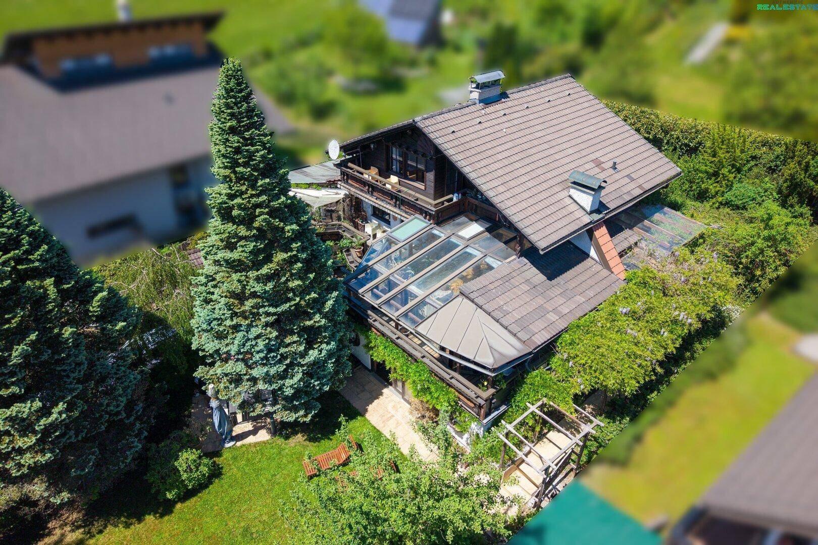 Luftaufnahme des Hauses mit Wintergarten, großem Garten und umgebender grüner Landschaft.