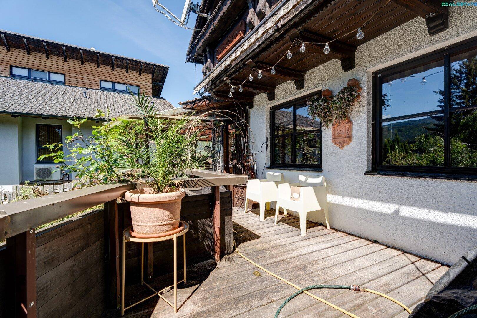 Sonniger Holzterrasse mit Sitzgelegenheiten und Blick auf die umliegende Natur.