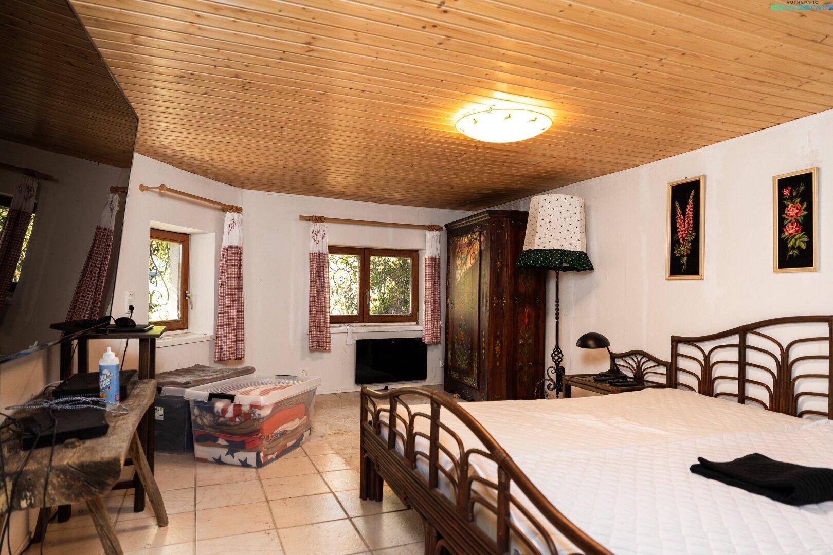 Gemütliches Schlafzimmer mit Holzbalkendecke, Fliesenboden und traditionellen Möbeln.