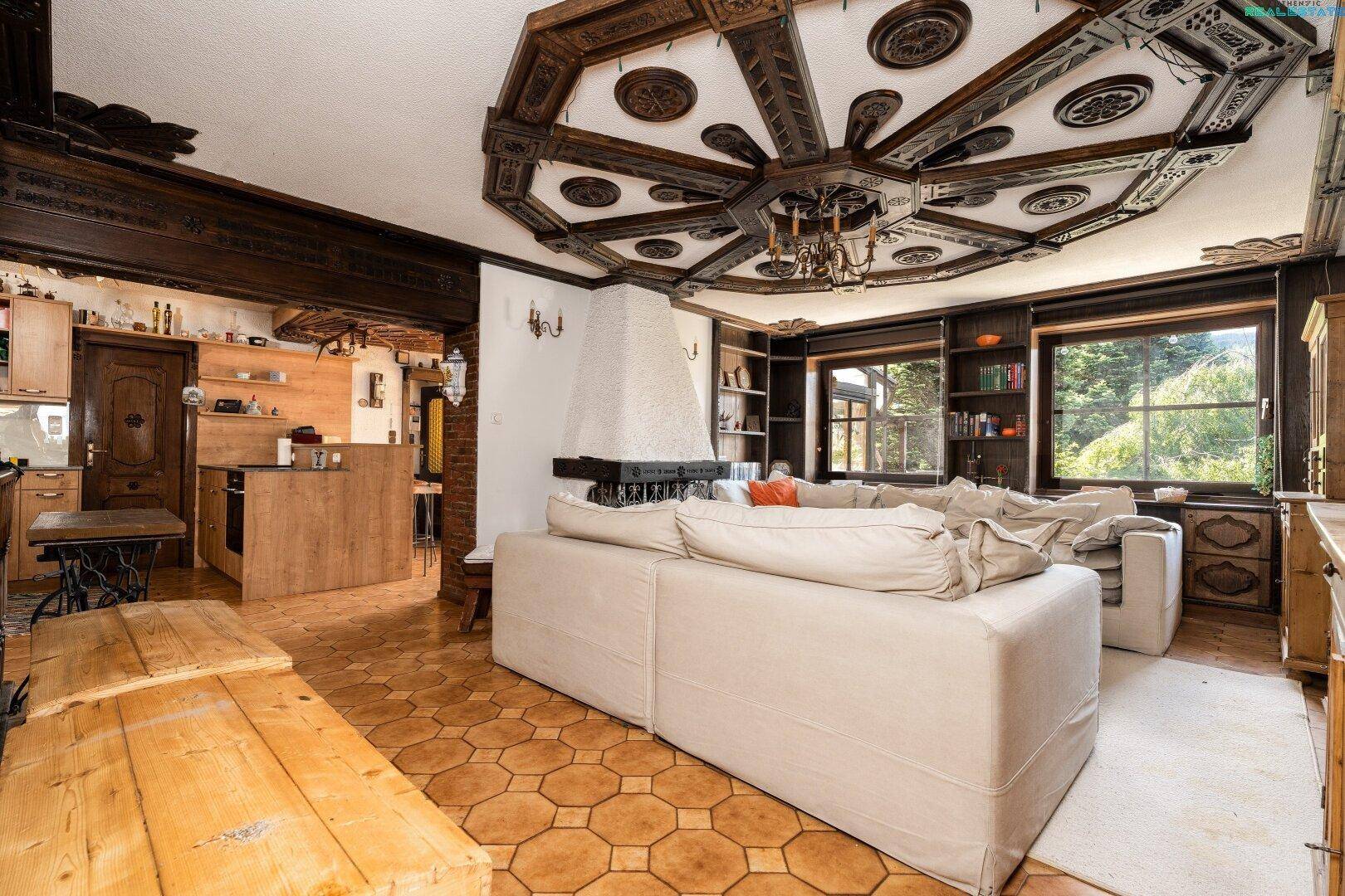Geräumiger Wohn-Essbereich mit kunstvoll geschnitzter Holzdecke, Kamin und Bergblick.