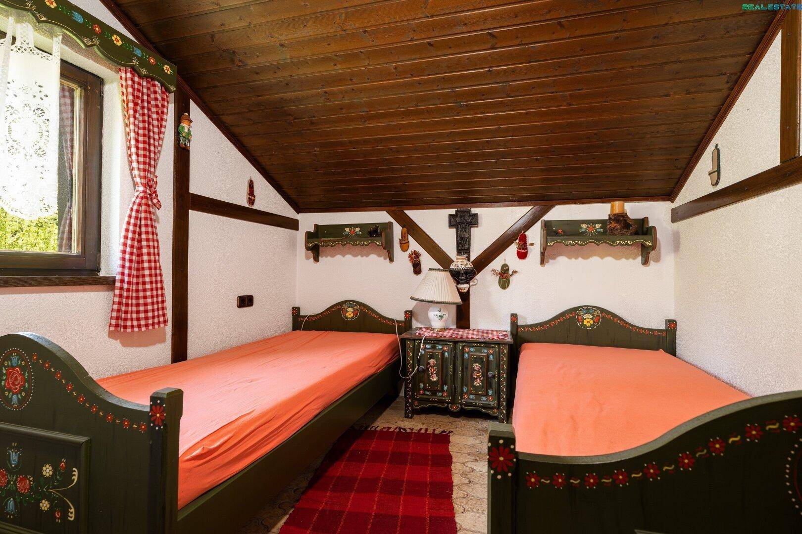 Kinderzimmer mit zwei Einzelbetten, bemalten Holzmöbeln und traditioneller Dekoration.