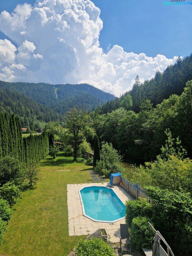 Gartenbereich mit Pool und atemberaubendem Blick auf die umliegenden Berge und Wälder.