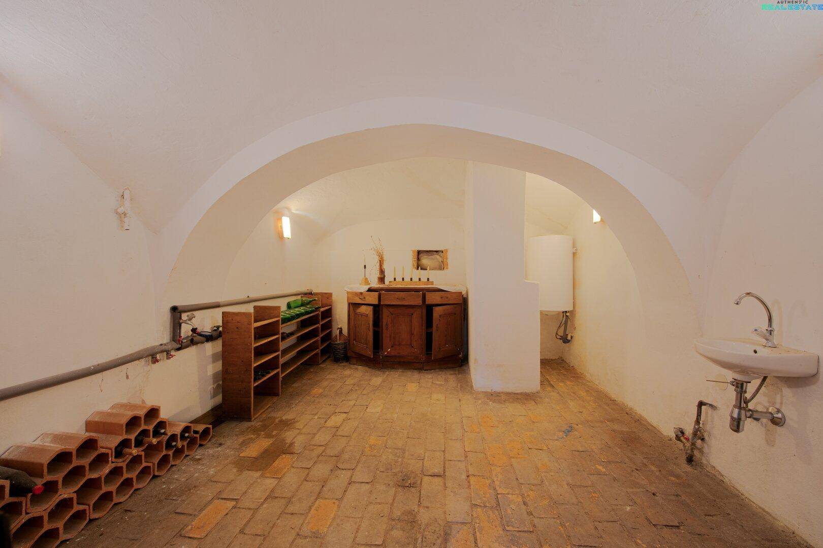 Gewölbekeller mit Ziegelboden, Weinregalen und einem Waschbecken, ideal zur Lagerung.
