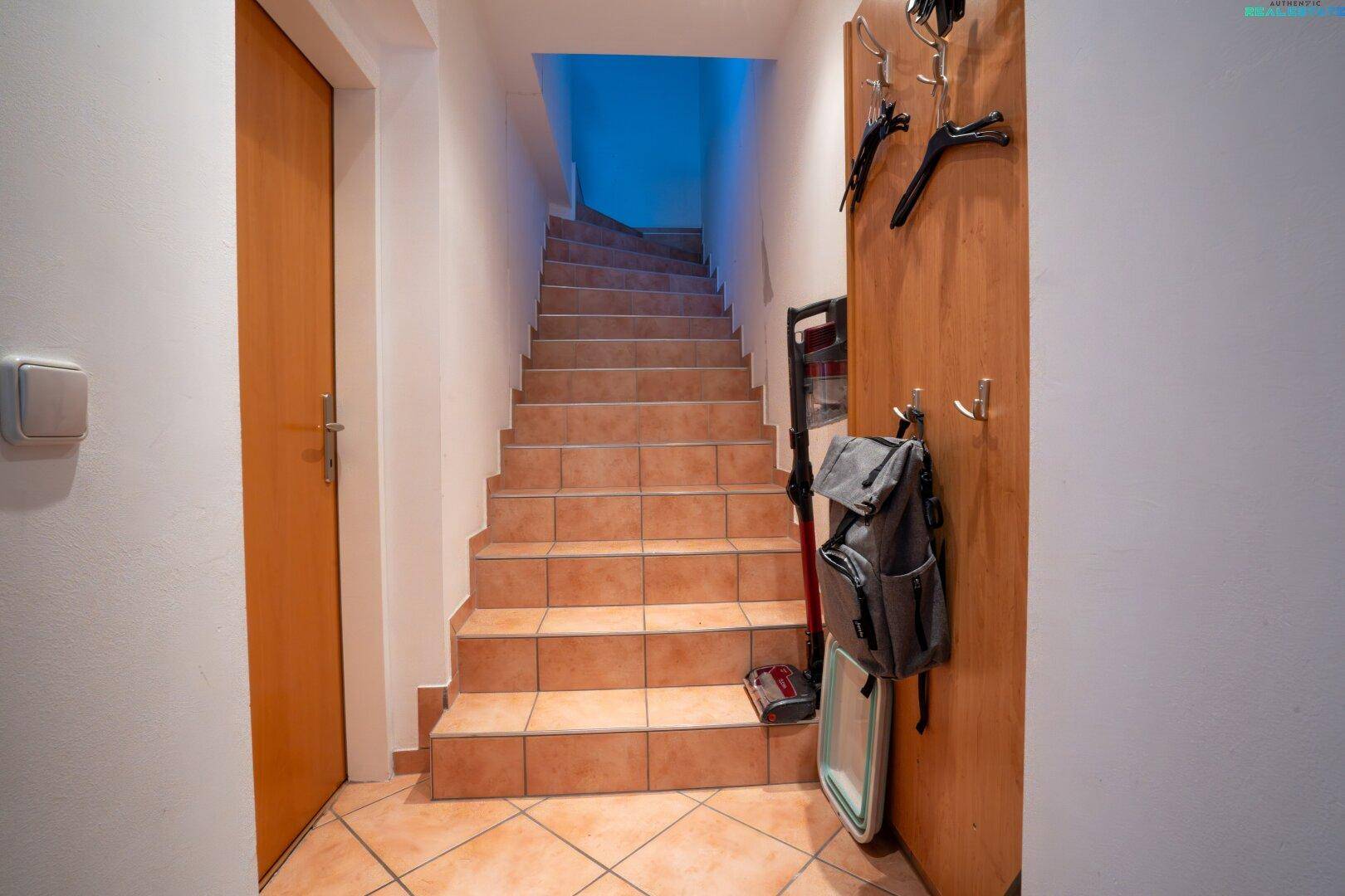 Geflieste Treppe führt in die oberen Etagen, mit praktischer Wandgarderobe.
