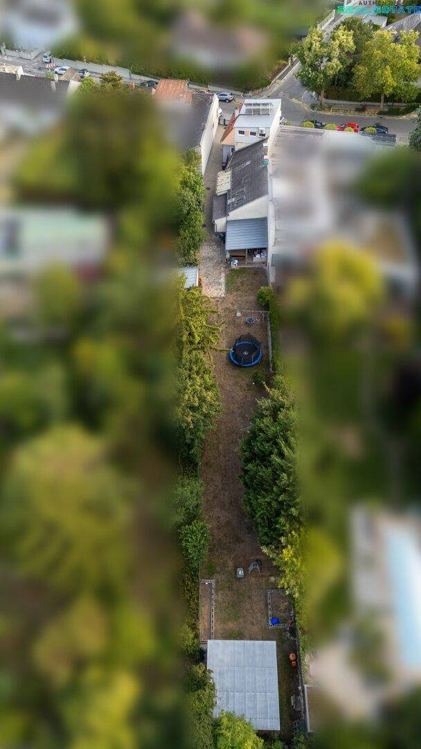 Luftaufnahme eines langen Gartengrundstücks mit Trampolin und angrenzenden Häusern.