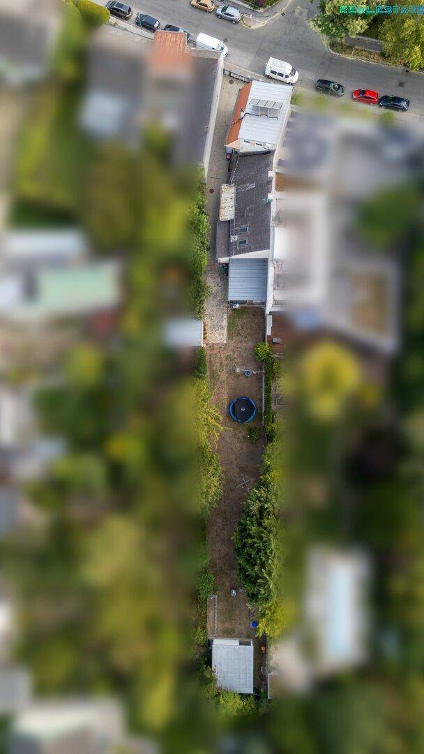 Vogelperspektive des weitläufigen Gartens mit Trampolin und umliegender Bebauung.