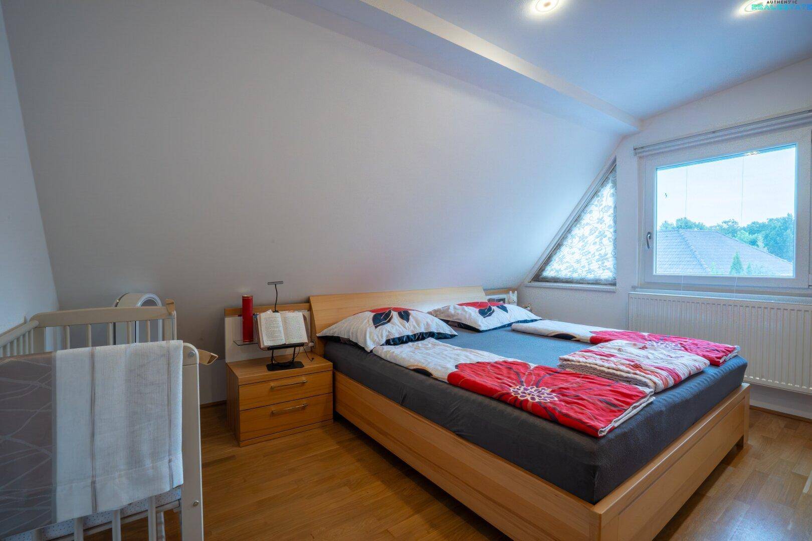 Helles Schlafzimmer mit Holzbett, Parkettboden und Dachschräge.