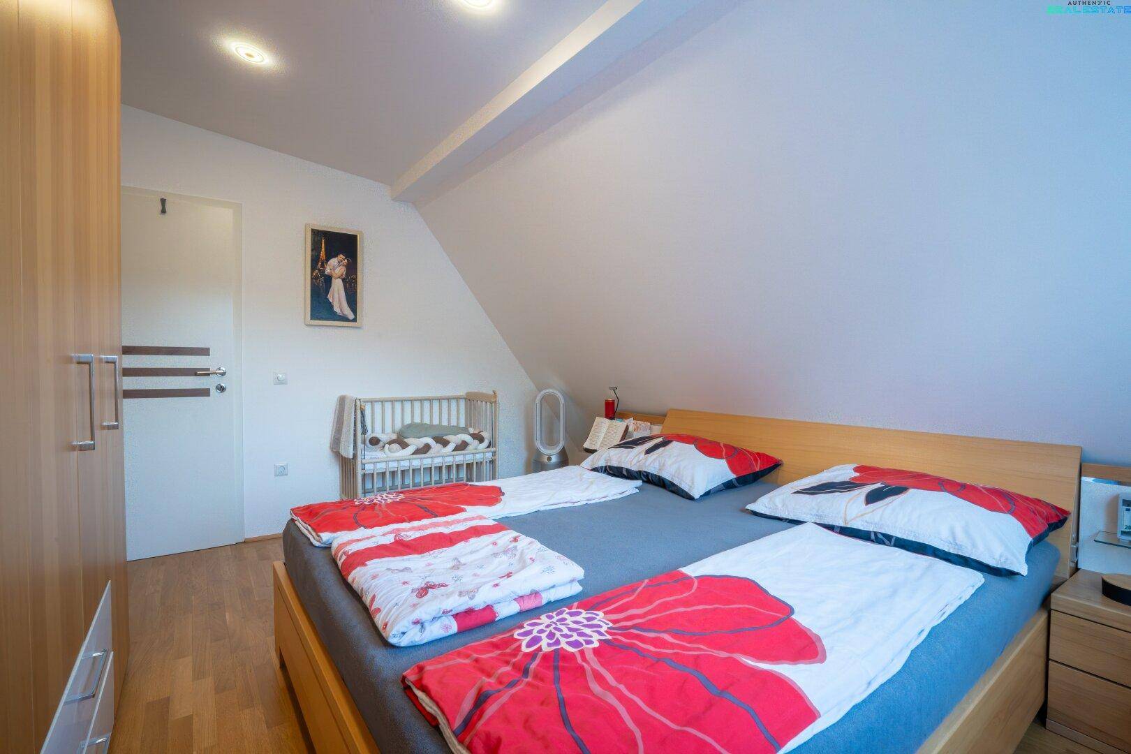 Schlafzimmer mit Holzbett, Kleiderschrank und Dachschräge, hell und freundlich.
