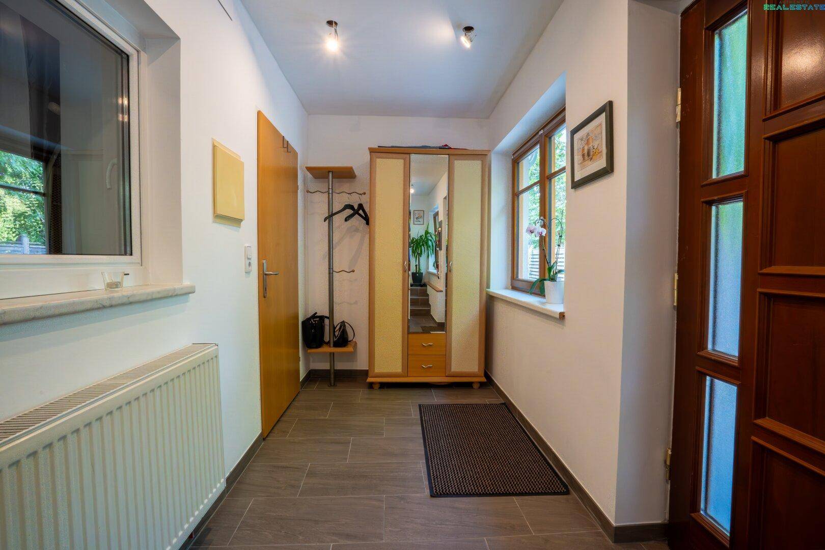 Freundlicher Flur mit gefliestem Boden, Garderobenschrank und Fenster, gut beleuchtet.