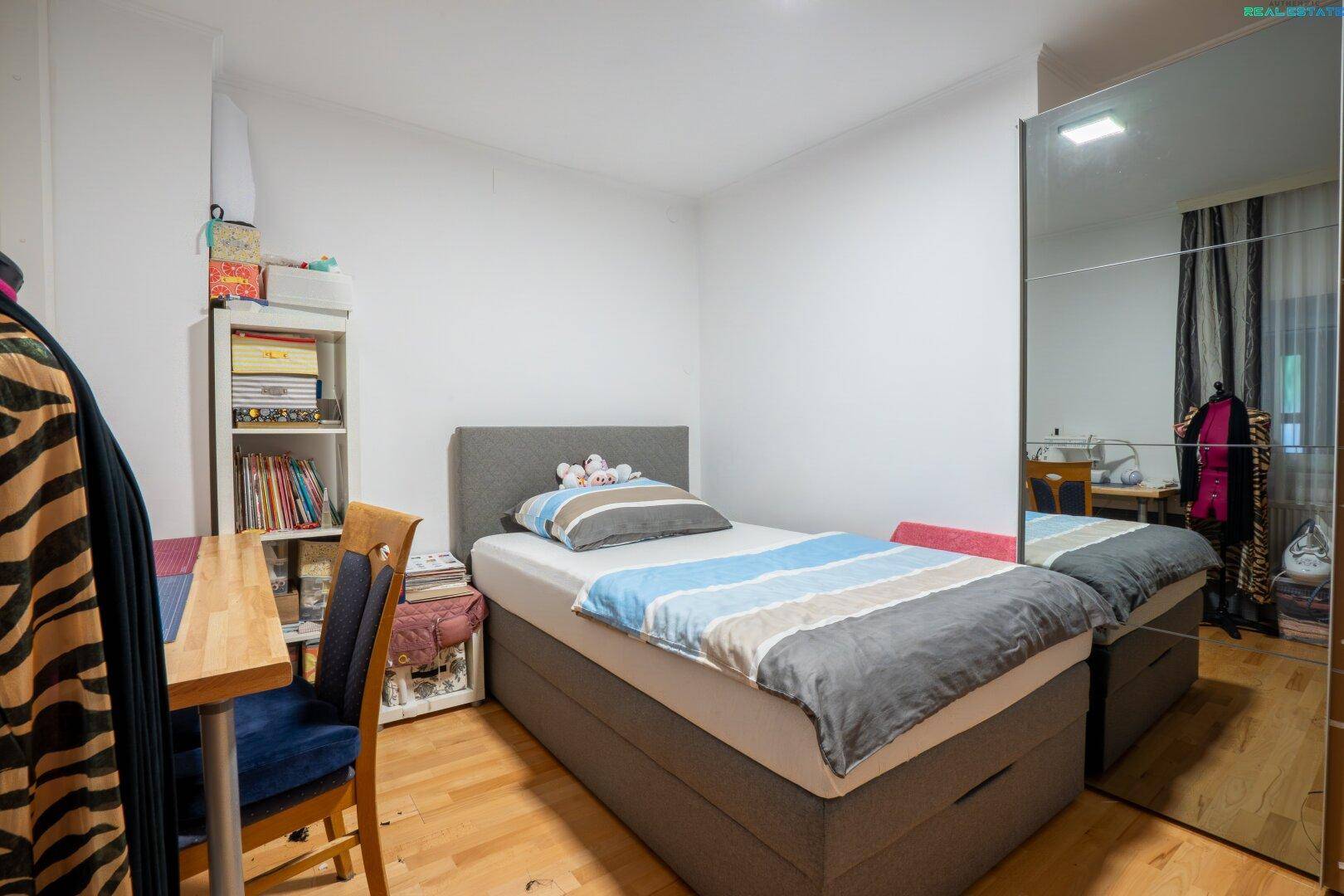 Gemütliches Schlafzimmer mit Einzelbett, Schreibtisch und großem Spiegelschrank.