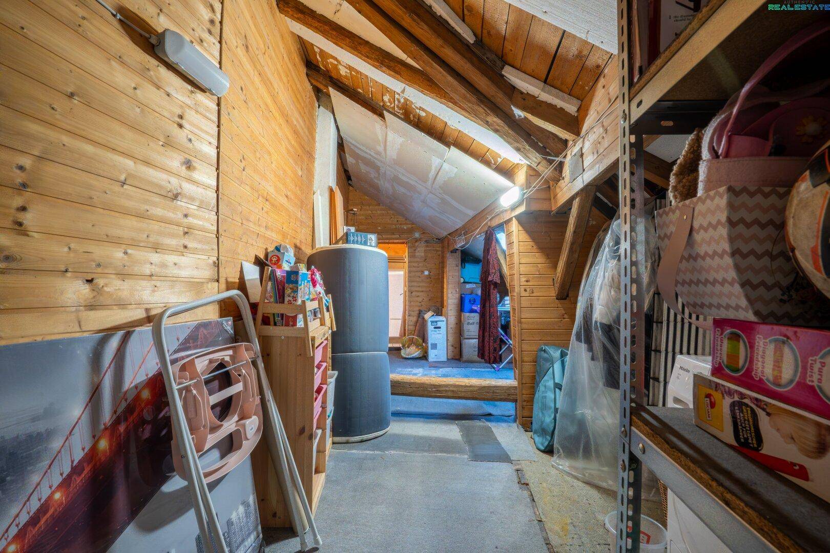 Rustikaler Dachboden mit Holzverkleidung und sichtbaren Balken, ideal als Stauraum.