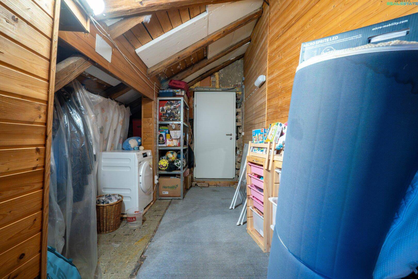 Geräumiger Dachboden mit Holzverkleidung, Stauraum und Waschmaschine, vielseitig nutzbar.