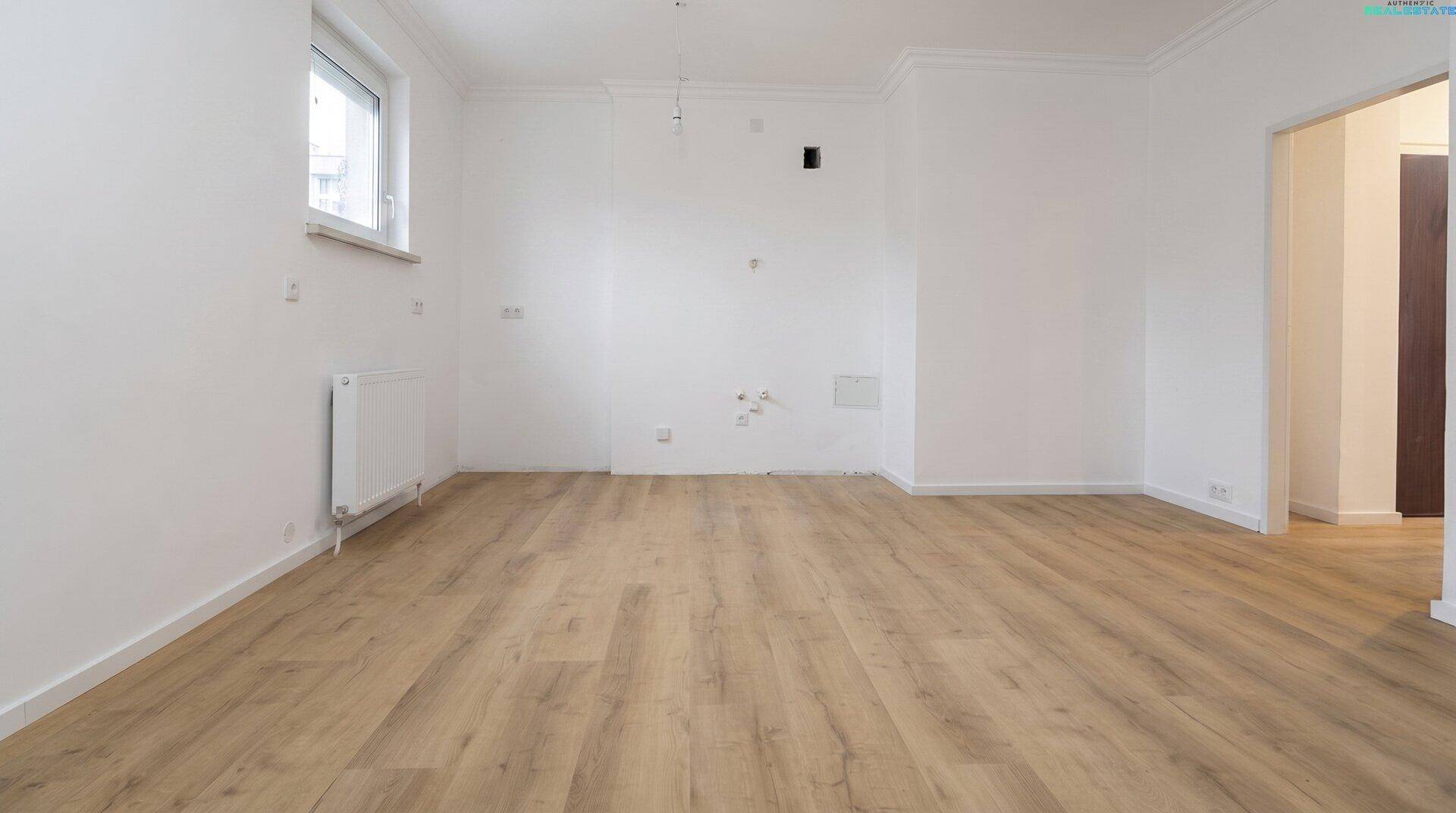 Heller Raum mit Holzboden und weißen Wänden, vorbereitet für eine Küche.