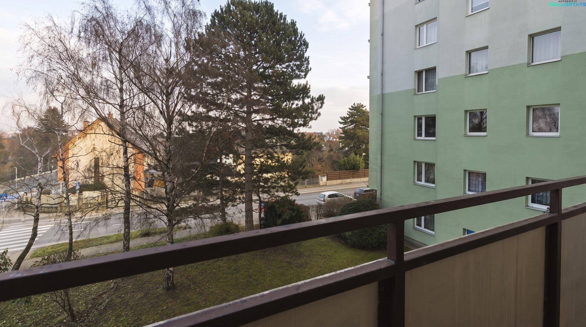 Balkon mit Blick auf die grüne Fassade eines Gebäudes und hohe Bäume.