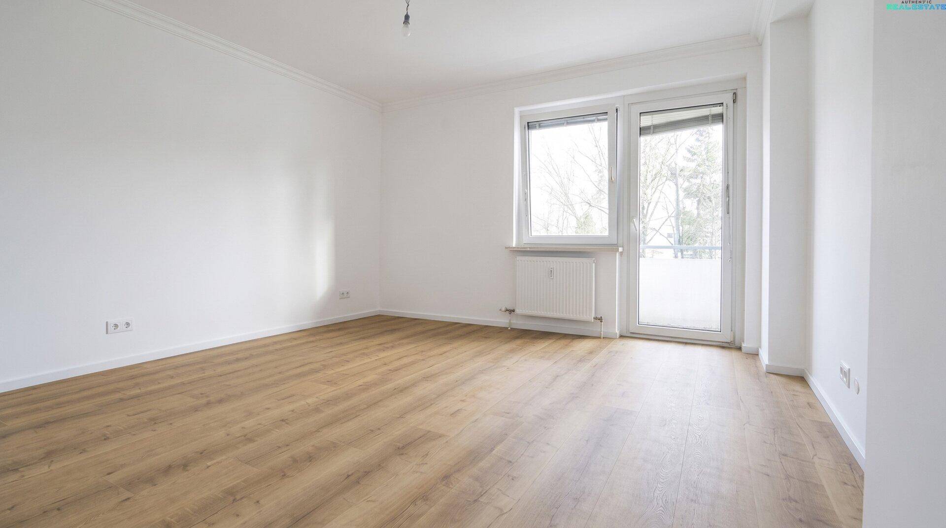 Heller Raum mit Holzboden, weißen Wänden und direktem Zugang zu einem Balkon.