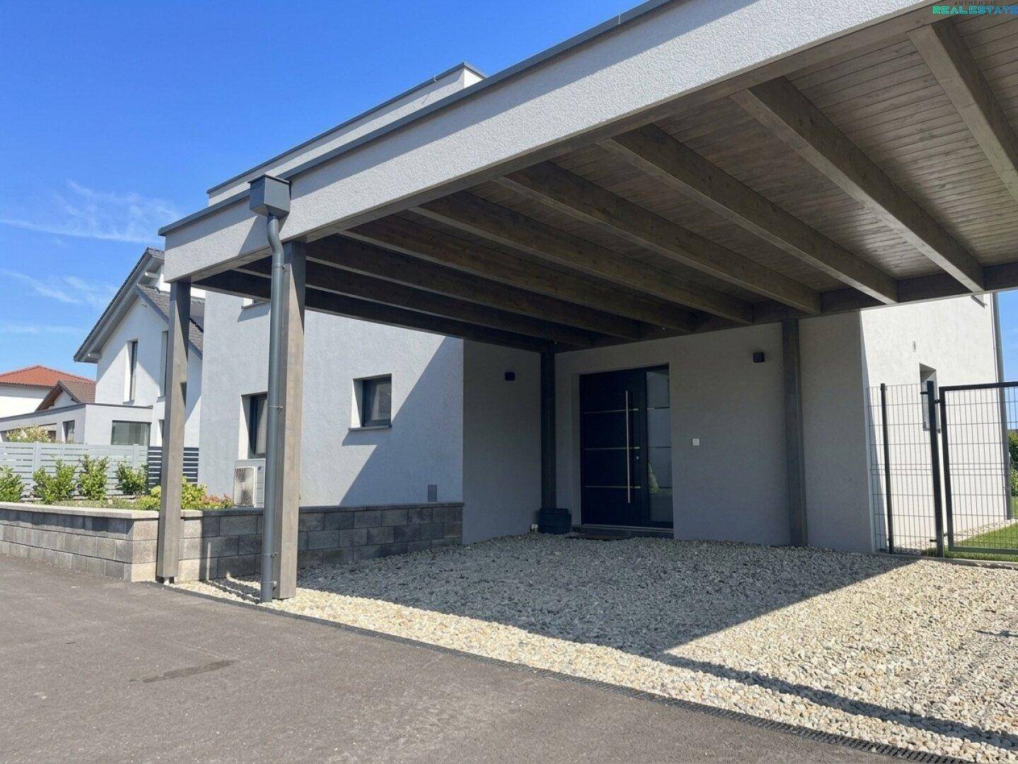 Eingangsbereich des modernen Hauses mit großem Carport und Kiesauffahrt.