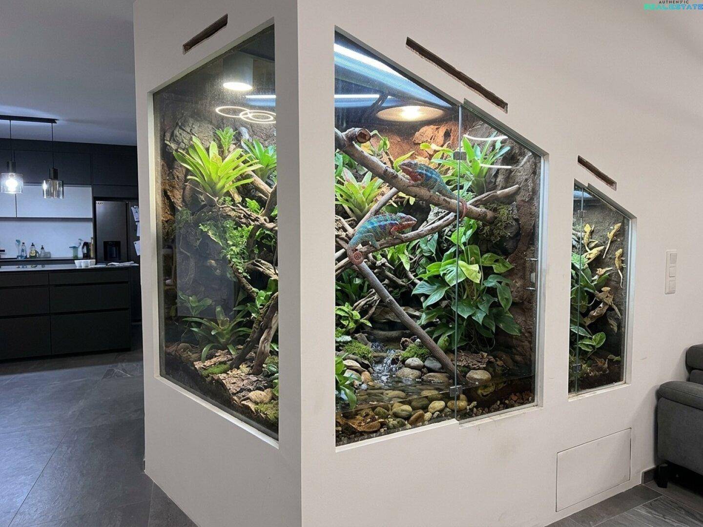 Wohnbereich mit einem großen, eingebauten Terrarium, das exotische Pflanzen und Tiere beherbergt.