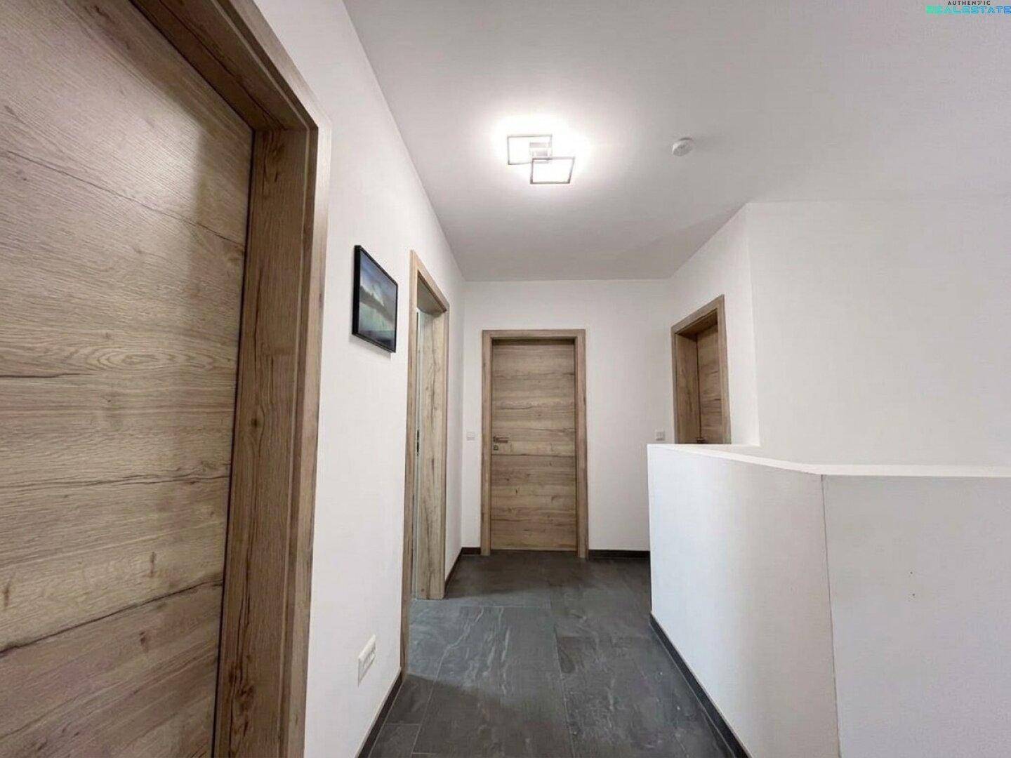 Heller Flur im Obergeschoss mit modernen Holztüren und schlichten weißen Wänden.