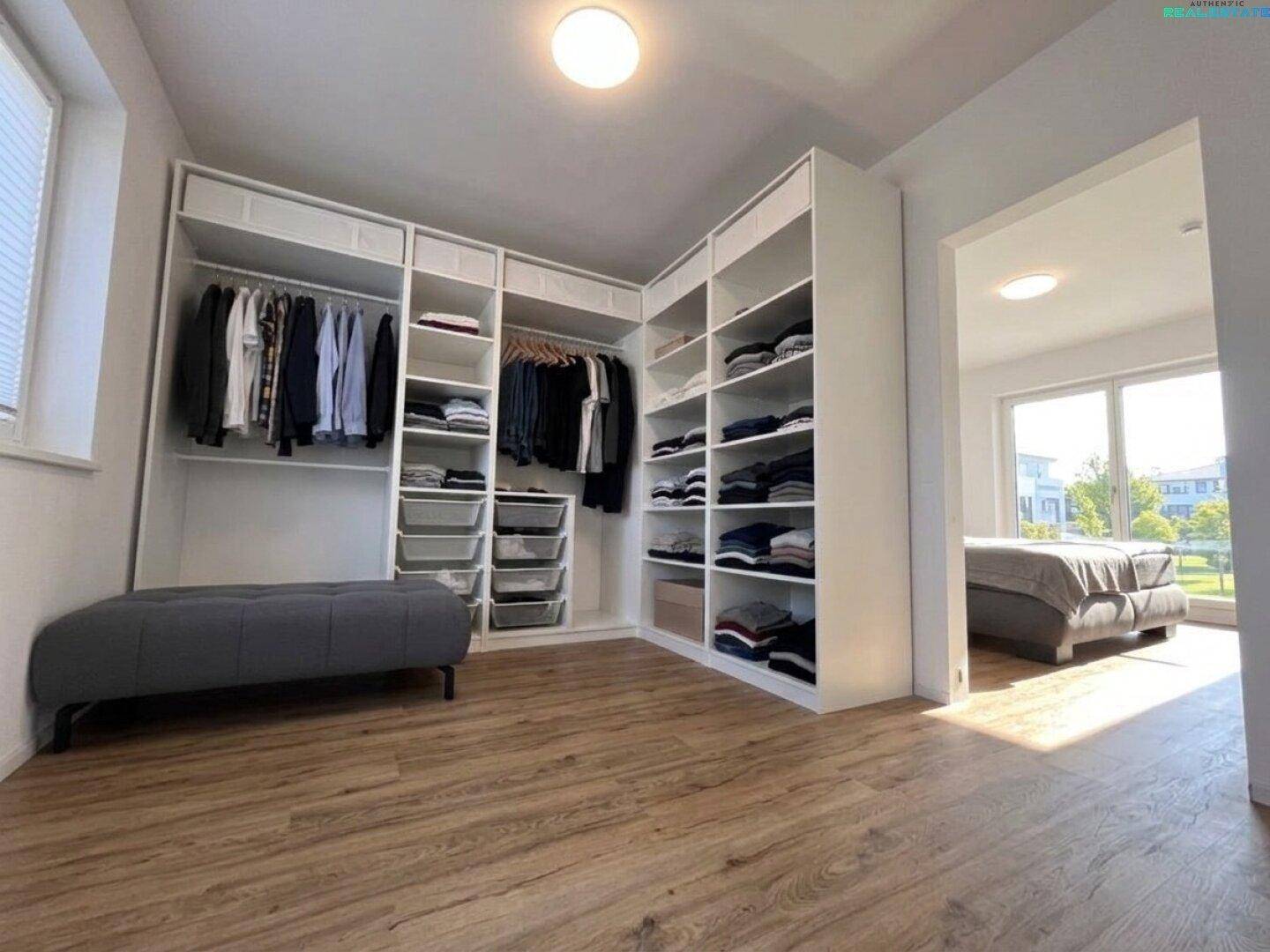 Geräumiger begehbarer Kleiderschrank mit viel Stauraum und Zugang zu einem hellen Schlafzimmer.
