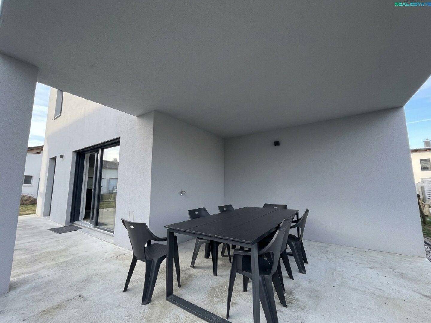 Überdachte Terrasse mit Esstisch und Stühlen, ideal für Mahlzeiten im Freien.
