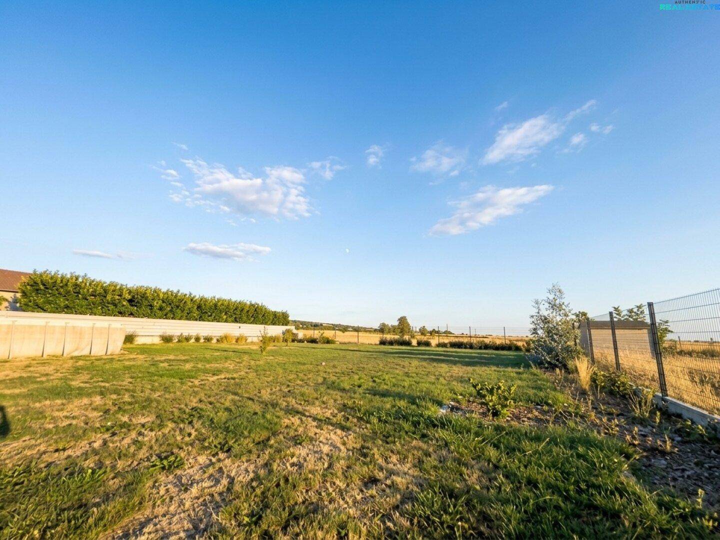 Weitläufiger Gartenbereich mit Rasenfläche und freiem Blick auf die umgebende Natur.