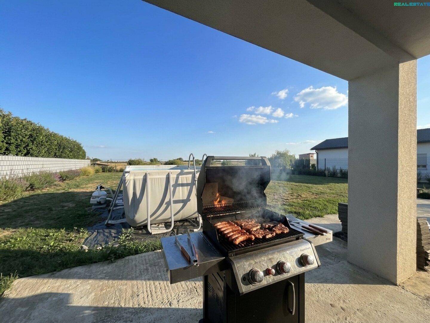 Grillbereich im Garten mit einem Gasgrill und einem kleinen Aufstellpool im Hintergrund.