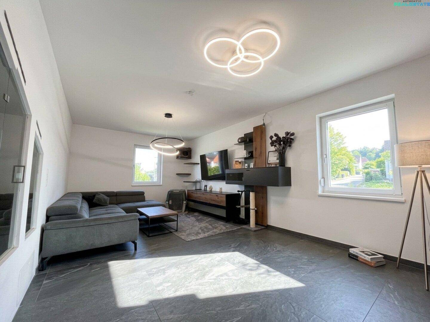 Gemütliches Wohnzimmer mit großem Sofa, moderner Medieneinheit und viel natürlichem Licht.