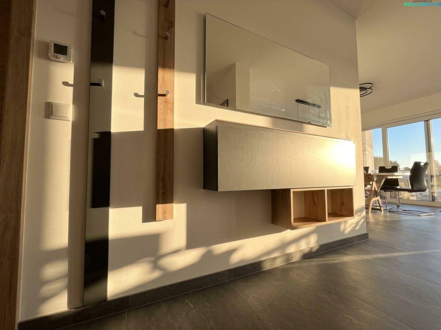 Heller Eingangsbereich mit modernem Spiegel, schwebendem Schrank und Garderobe, sonnendurchflutet.