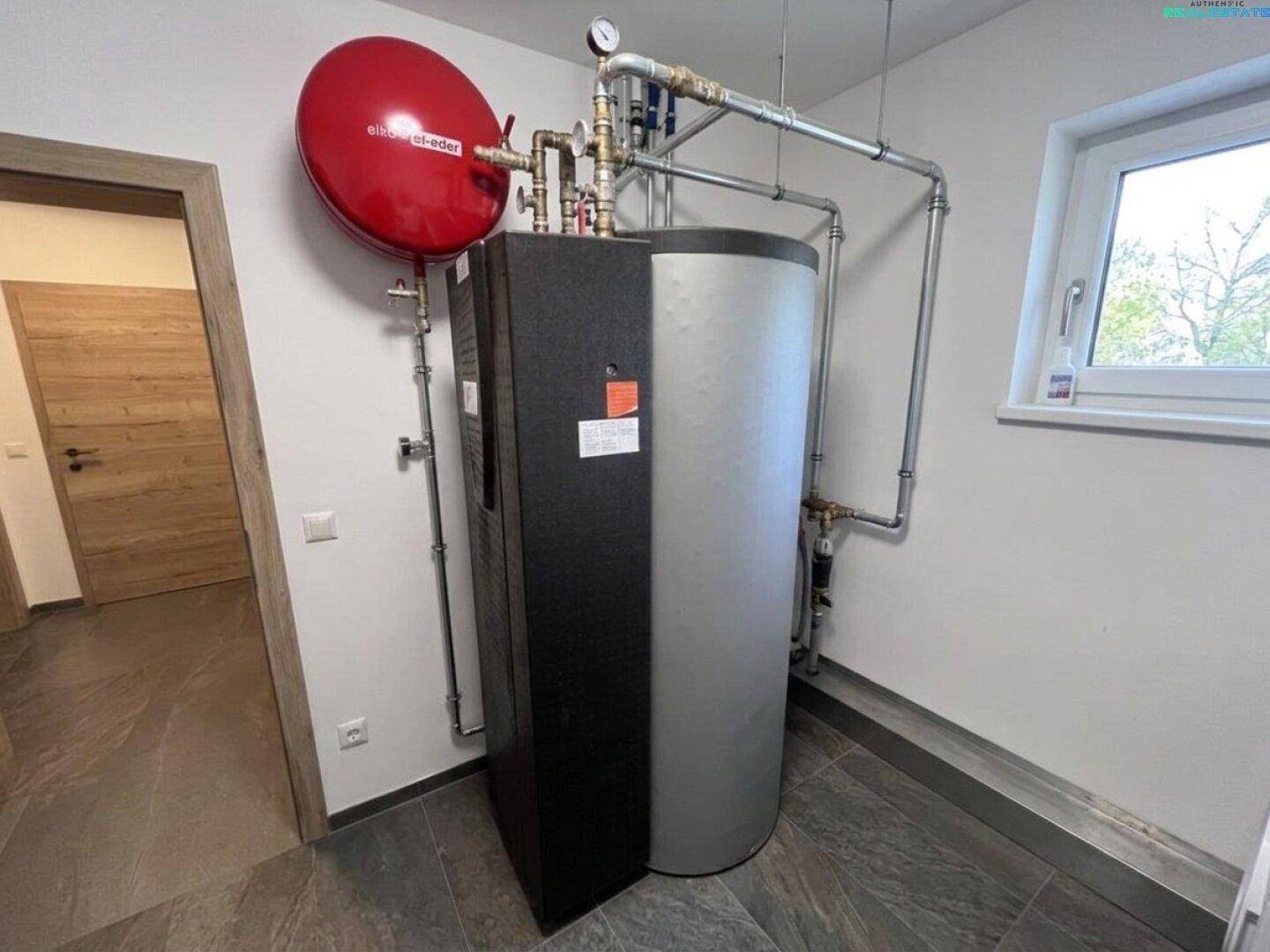 Hauswirtschaftsraum mit moderner Heizungsanlage und Warmwasserspeicher sowie einem Fenster.