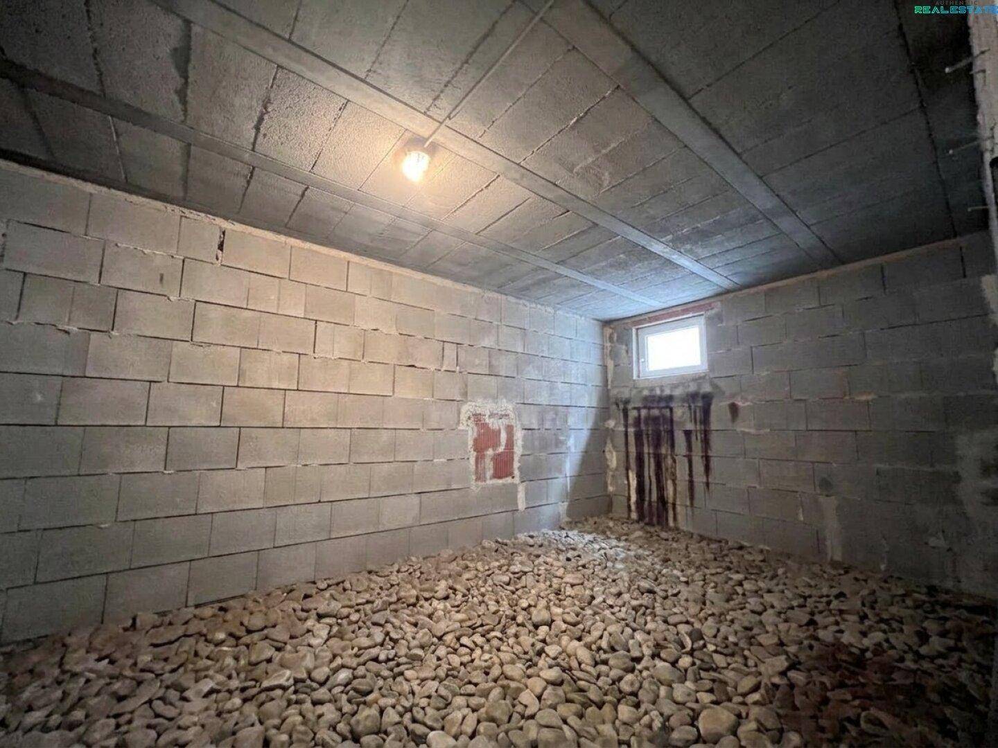 Unausgebauter Kellerraum mit Kiesboden und unverputzten Wänden, ideal für Lagerung.