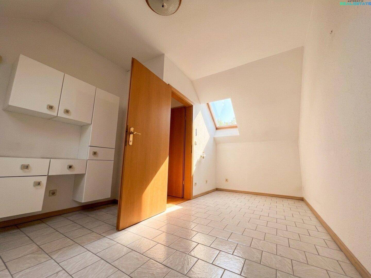 Dachzimmer mit Fliesenboden, Dachfenster und Einbauschränken für zusätzlichen Stauraum.