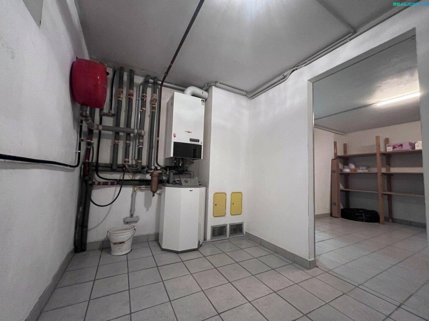 Heizungsraum im Keller mit moderner Heizungsanlage und Warmwasserspeicher.