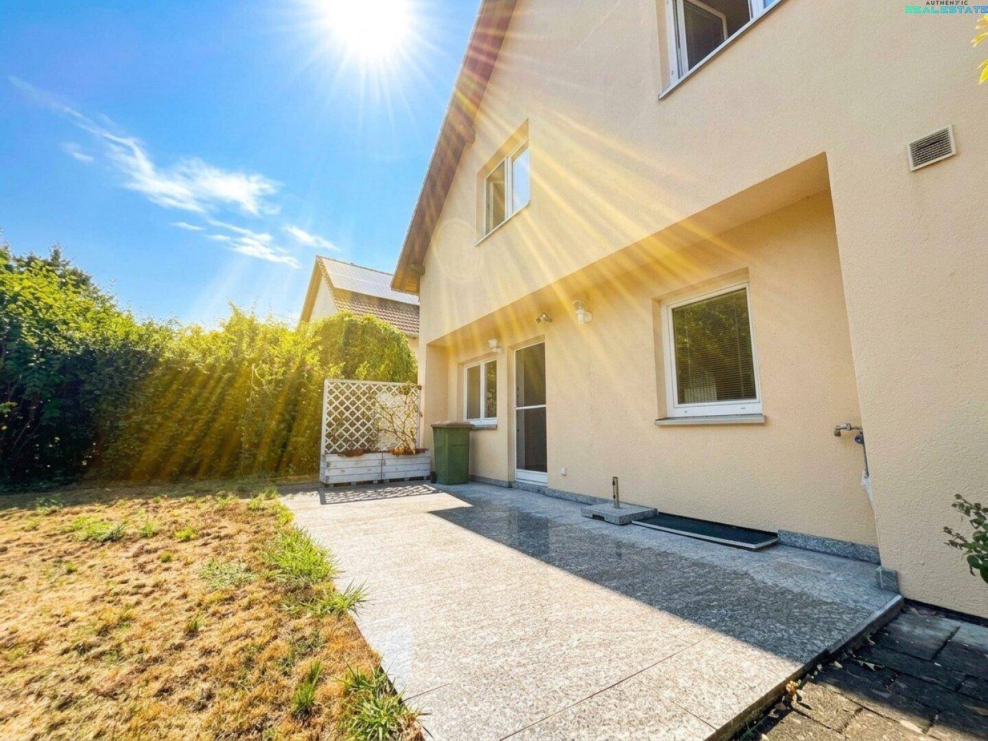 Sonniger Terrassenbereich mit Granitplatten und Zugang zum Garten, ideal für Entspannung.