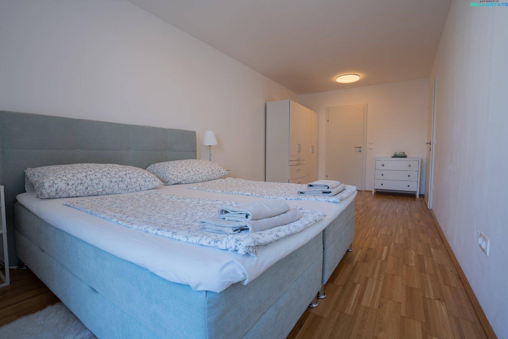 Schlafzimmer mit Doppelbett, Kleiderschrank und Holzboden.