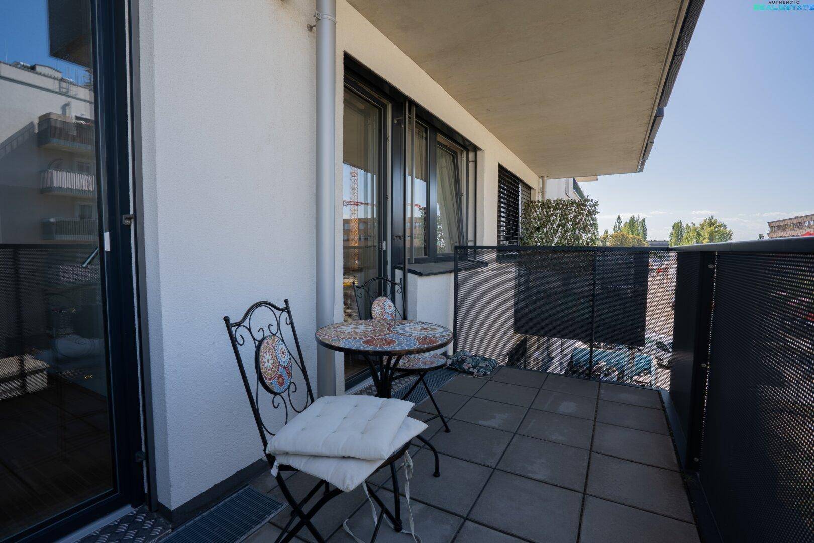Gemütlicher Balkon mit Sitzgelegenheiten und Blick auf die moderne Fassade des Gebäudes.