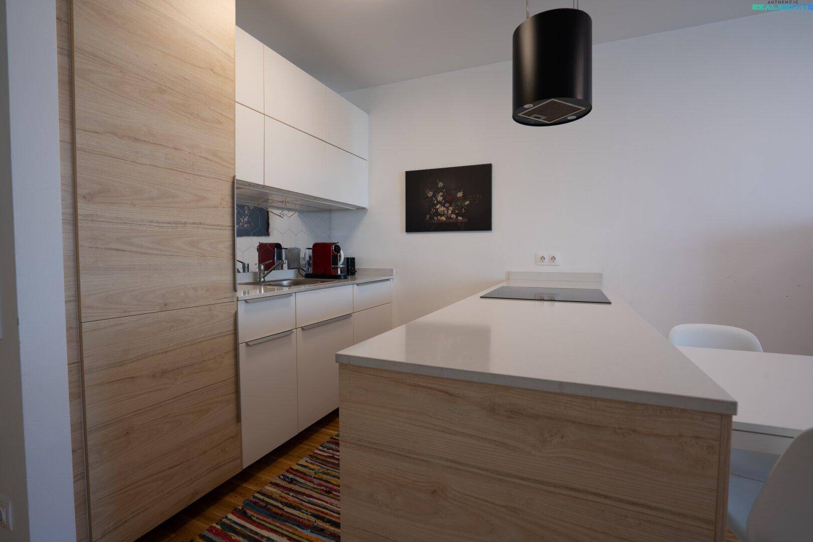 Moderne Küche mit hellen Holz- und weißen Schränken, Induktionskochfeld und Essbereich.