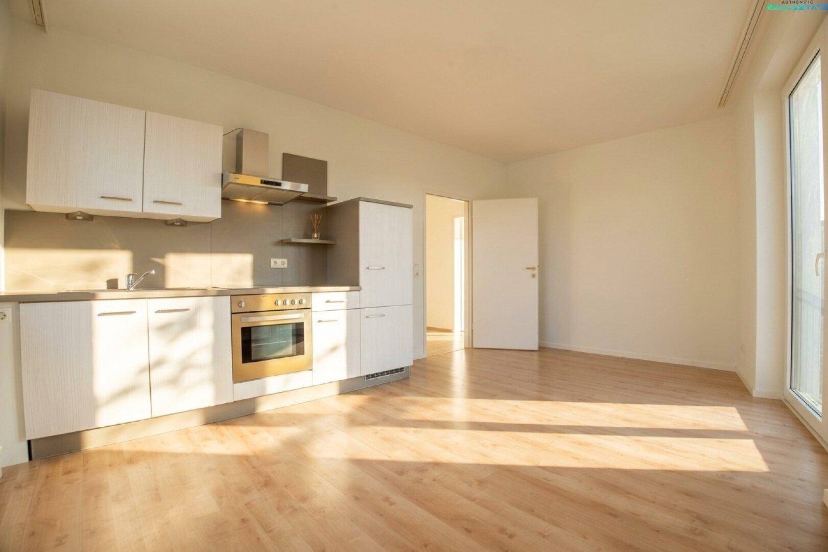 Heller Raum mit moderner Küchenzeile, Zugang zu einem Außenbereich und sonnigem Laminatboden.