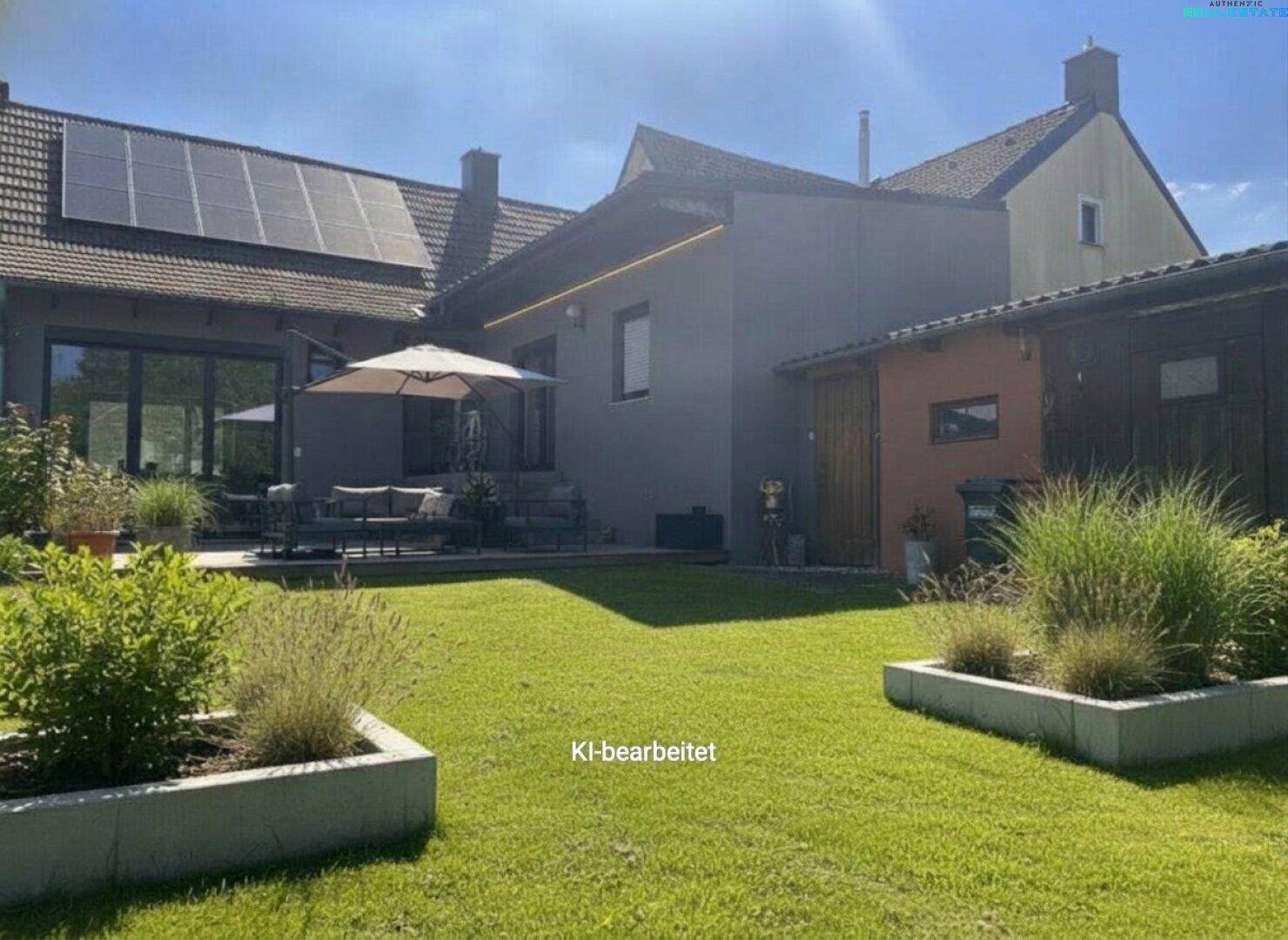 Gepflegter Garten mit großer Terrasse, Sitzgelegenheiten und Photovoltaikanlage auf dem Dach.