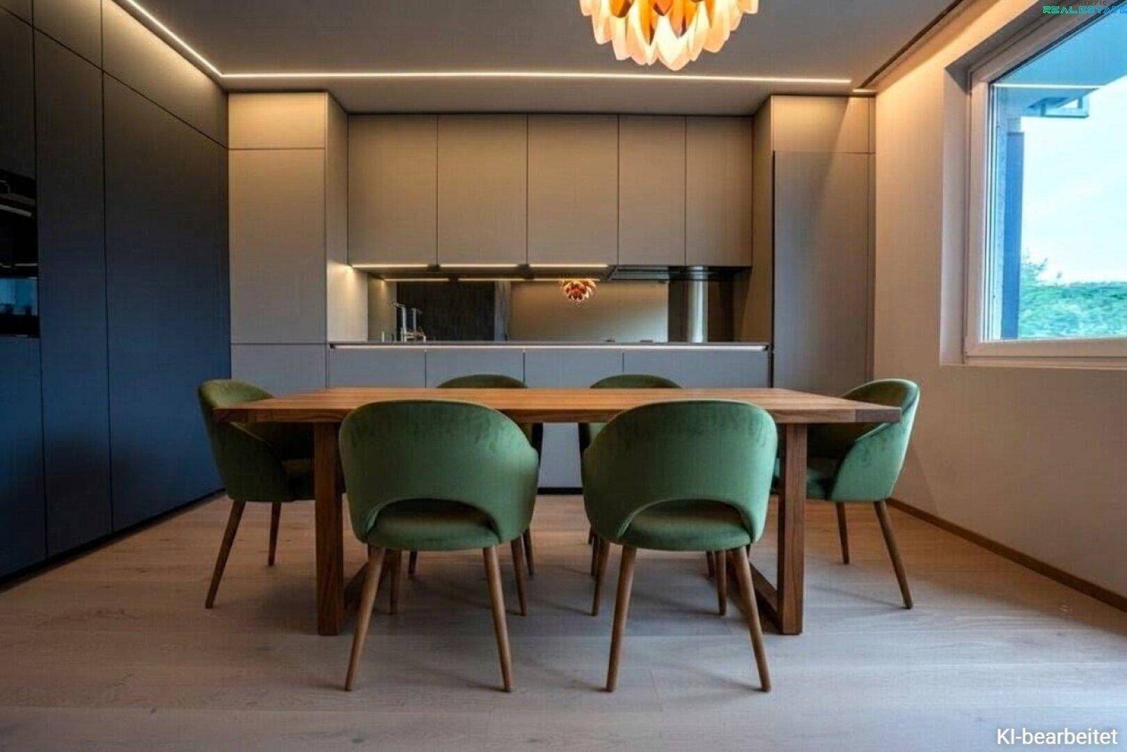 Eleganter Essbereich mit Holztisch, grünen Samtstühlen und moderner Küchenzeile im Hintergrund.